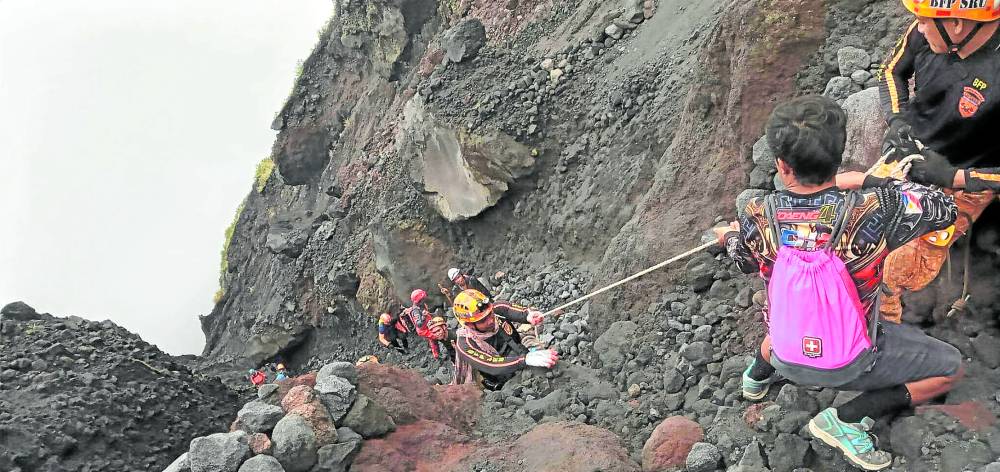 Members of the team tasked to find the Cessna plane that crashed on Mt. Mayon on Feb. 18 make their way toward the wreckage on a gullynear the volcano’s summit crater on Thursday