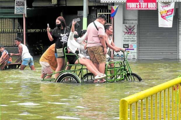 ‘FLOOD SELFIE’ Passengers of a pedicab take out their mobile phones for a “selfie” as they pass through a flooded street at the city center of Dagupan on July 30. For more than a week now, a large part of the city has been flooded due to the recent heavy rains, high tide and overflowing rivers. —WILLIE LOMIBAO